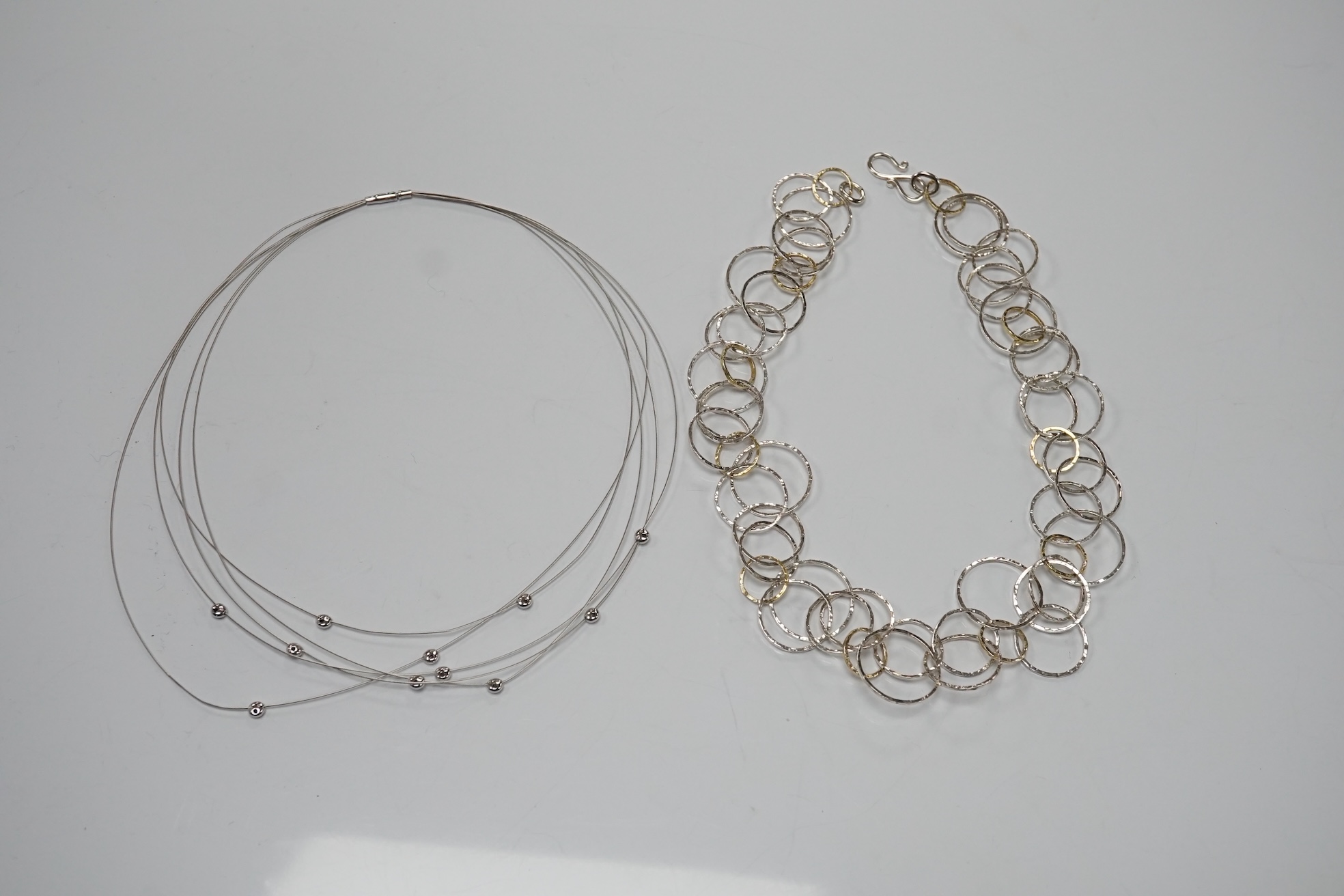 A modern Pruden & Smith silver and yellow metal hoop necklace and a 750 white metal and diamond set multi strand necklet retailed by Mappin & Webb. Condition - fair to good